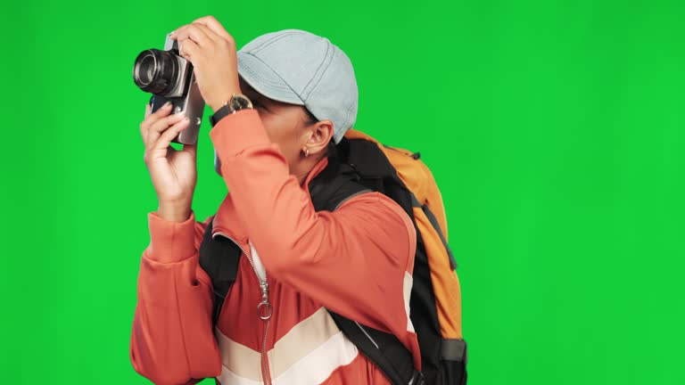 Woman, hiking and green screen with travel and photography, trekking and taking picture on studio background. Mockup space, vacation and sightseeing with young female hiker, camera and adventure