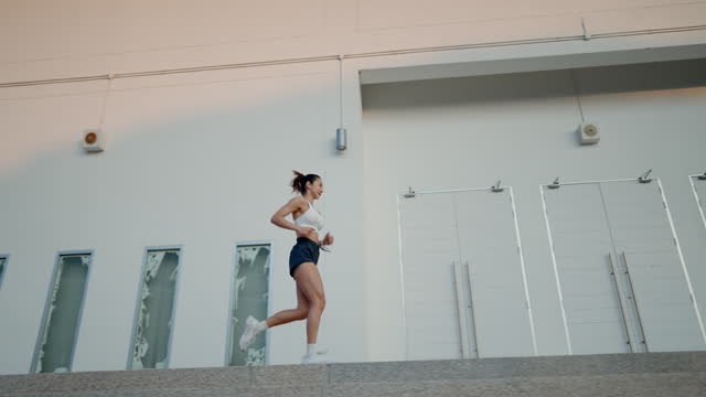 A woman runs up a set of stairs in front of a white building