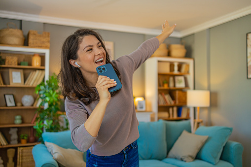 Photo of beautiful woman singing and dancing in living room