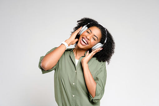 A vibrant African-American lady is captured mid-dance, her smartphone in hand, enjoying her favorite tunes, showcasing a moment of carefree joy and music appreciation.