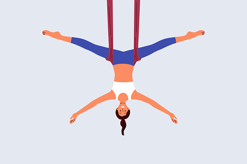 Woman practices aerial yoga, doing suspended stretching exercises to improve body health and flexibility. Aerial yoga trainer girl recommends enrolling in pilates or aerobics courses