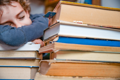 Schoolboy Sleeping on the Table Full of Books