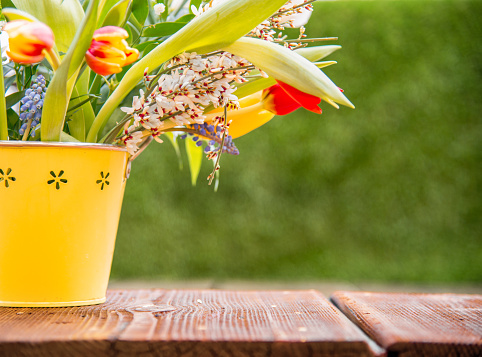 Flowers in a Yellow Bucket on an Old Wooden Table with Copy Space