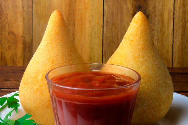 Coxinha in the dish, traditional Brazilian cuisine snacks stuffed with chicken, on rustic wooden table