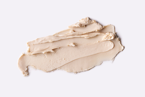 Close-up view of a textured cosmetic clay. Cosmetic product beige texture with visible strokes and ridjes, highlighting its smooth and soft.