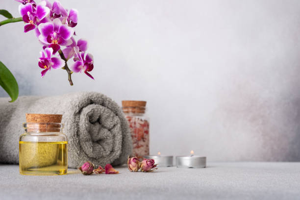 istock A serene spa still life featuring essential oils, smooth pebbles, a rolled grey towel, and a vibrant purple orchid 2104263790