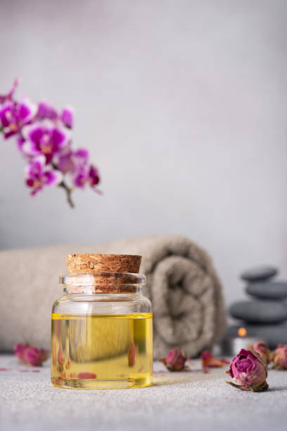 istock A serene spa still life featuring essential oils, smooth pebbles, a rolled grey towel, and a vibrant purple orchid 2104264302