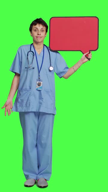 Front view Medical assistant holding a red speech bubble icon against greenscreen