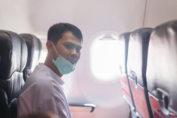 istock Man Wearing Mask Sitting in Airplane Cabin 2104293881