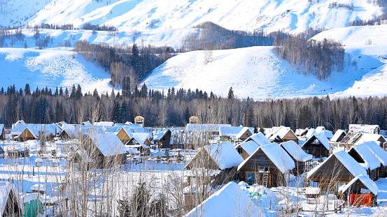 Log cabin village in winter, houses on hill neighborhood blanketed with snow in Xinjiang, China, Jan 2024