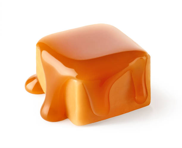 One beautiful sweet caramel candy cube topped with caramel sauce isolated on white background