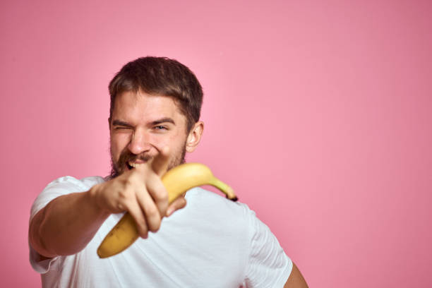 istock bearded man with banana in hand on pink background fun emotions model 2104344064