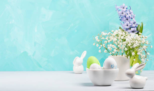 istock Still life of Easter small white ceramic bunnies, decorative eggs, jacinth and gypsophila flowers. 2104380767