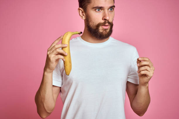 istock bearded man with banana in hand on pink background fun emotions model 2104381287