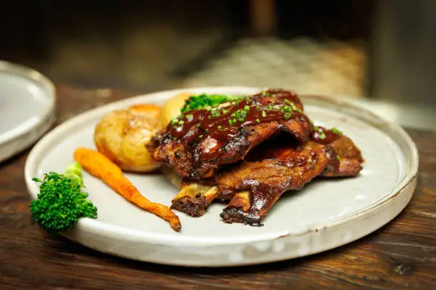 Succulent Grilled Ribs Feast: A succulent serving of grilled ribs, glazed with a rich, glossy sauce and garnished with fresh greens