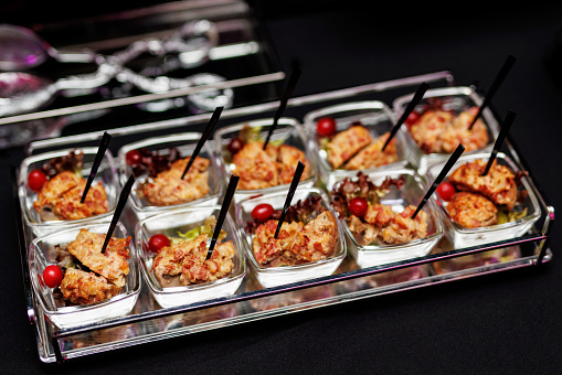 Upscale Appetizer Showcase: An enticing assortment of bite-sized delicacies, elegantly presented in transparent square bowls.