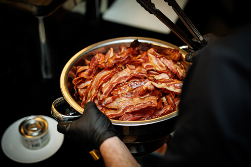 Crispy Bacon: glistening texture of dry cooked bacon in a chef hands