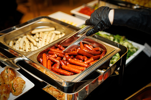 Grilled sausages in a metal tray at a hotel breakfast buffet
