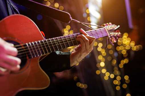 A musician plays a chord on an acoustic guitar during a performance.