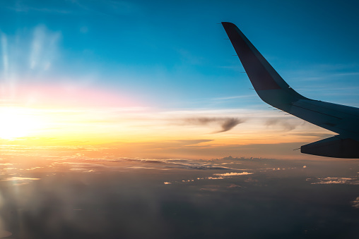A vibrant sunrise scene captured from the perspective of an airplane passenger, showcasing the wing and clouds.