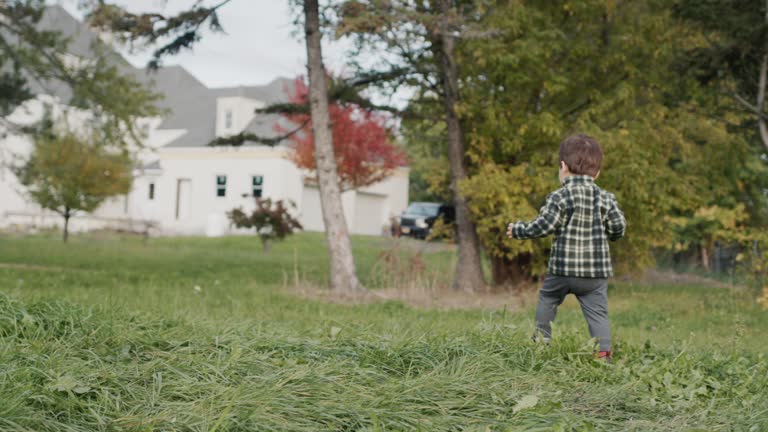 An active farm boy walks in the yard, eats a big apple on the go