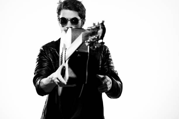 istock A man plays the guitar in a black leather jacket with sunglasses on a light background 2104445763