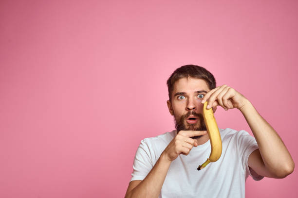 istock bearded man with banana in hand on pink background fun emotions model 2104488428