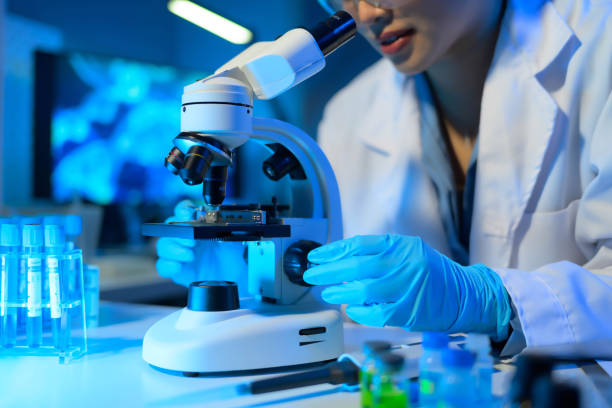 istock A woman in a lab coat is using a microscope to examine a sample 2104492029