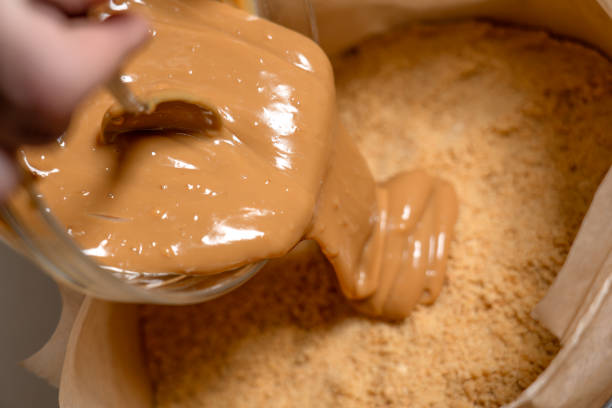 istock Pour caramel sauce into springform with ground cookies base. Cooking Salted Caramel Chocolate Cold Cake Series. 2104493199