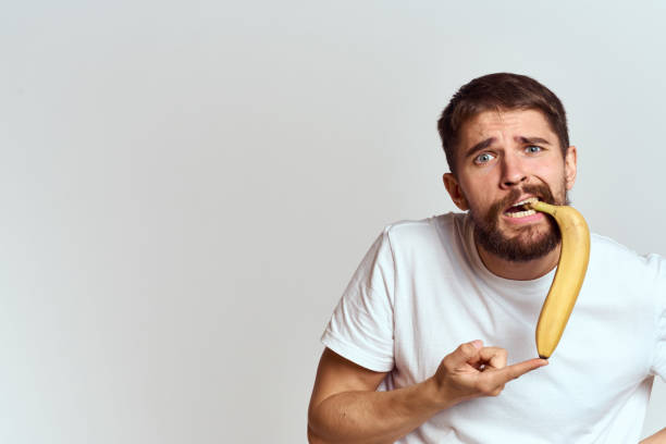 istock Cheerful man with a banana in his hands on a light background fun emotions Cropped view Copy Space 2104497028