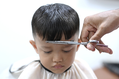 Trimming hair with scissors on boy