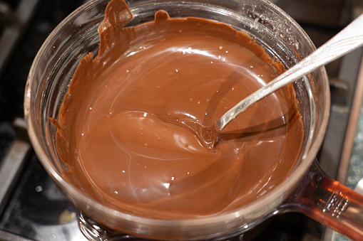 Melt chocolate in glass bowl over a pot of boiling water on gas stove. Cooking Salted Caramel Chocolate Cold Cake Series.