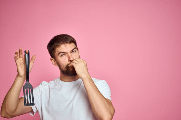 istock Man with spatula in hands kitchen accessories model emotions pink background cropped view Copy Space 2104510431