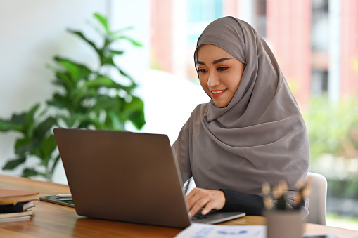 Young Muslim Businesswoman with hijab working with laptop and doing financial report.