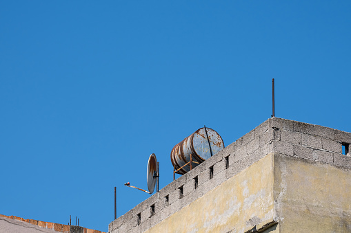 rusty water tank and satellite dish on the roof of old house.