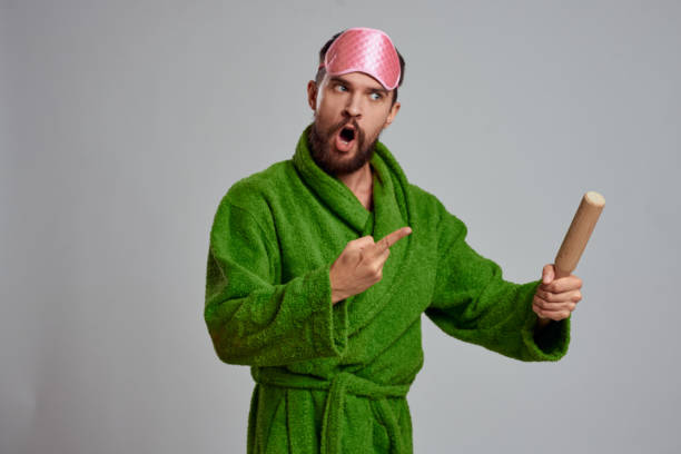 istock man with rolling pin in hand green robe pink sleep mask cropped view 2104537217