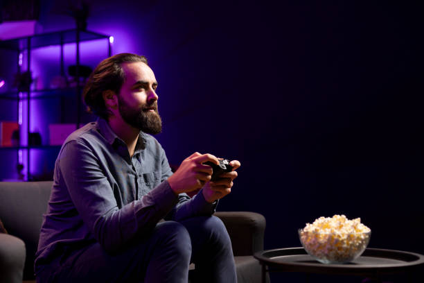 istock Man in home theatre playing videogames and consuming snacks 2104556734
