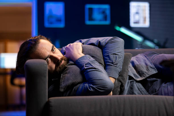 istock Man laying down hugging pillow watching TV, heartbroken by glum movie plot 2104565146