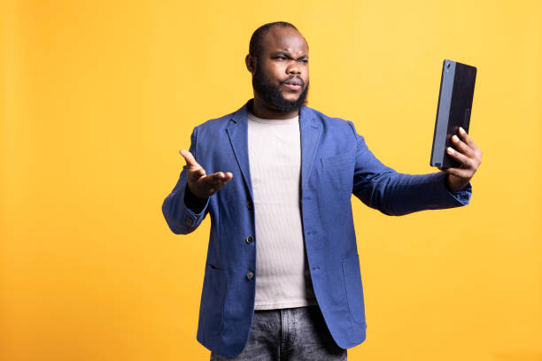 istock Offended man fighting with friends in tablet videocall, studio background 2104579542