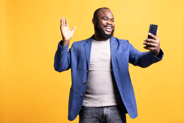 istock Cheerful man excited to greet friends during videocall, studio background 2104583276