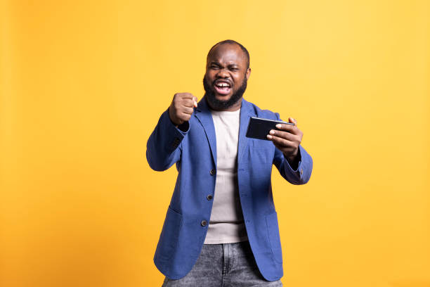 istock Happy person plays videogames on smartphone, celebrating, clenching hand gesture 2104583830