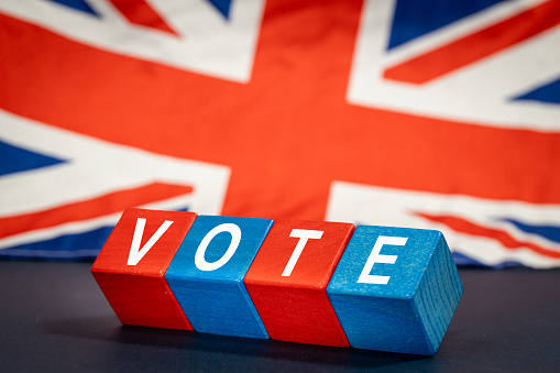 Great Britain vote, the word Vote on wooden blocks against the background of the British flag, the concept of voting and taking part in important state and local elections