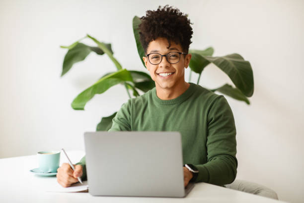 istock Cheerful stylish black guy freelancer working at cozy cafe 2104631676