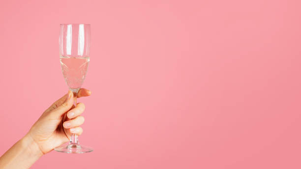 istock A close-up image showing a hand elegantly holding a sparkling champagne flute with effervescent bubbles 2104632865
