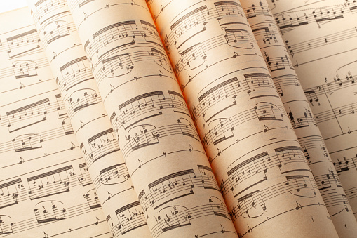 male composer playing piano and writing a song on music sheet