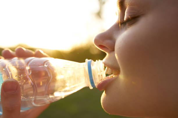 istock woman drinks water from a plastic bottle outdoors in summer 2104643913