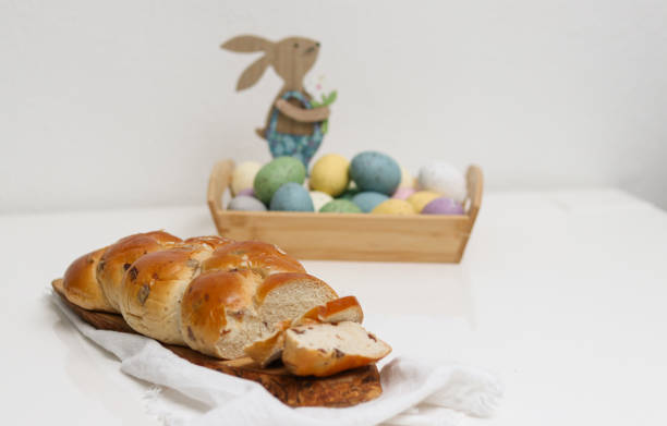 istock Cutted easter loaf bread on wooden plate on white table 2104649328