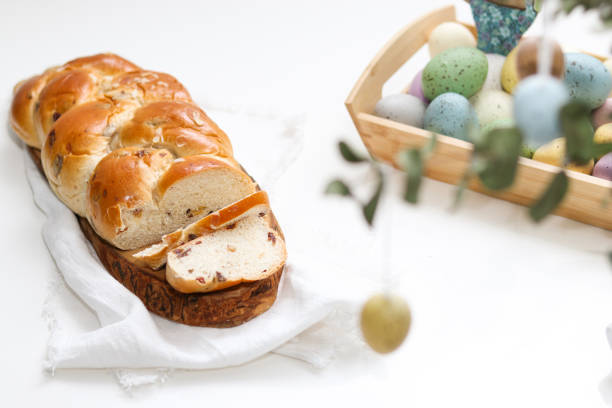 istock Cutted easter loaf bread on wooden plate on white table 2104649334