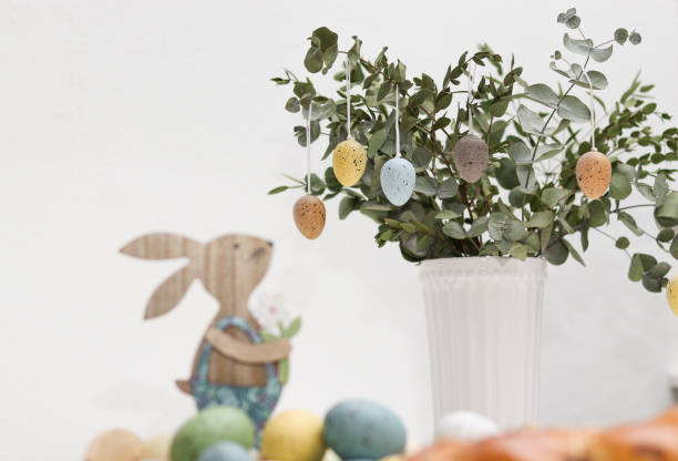 istock Colorful easter eggs hanging decorative on eucalyptus plant in a white vase 2104649888