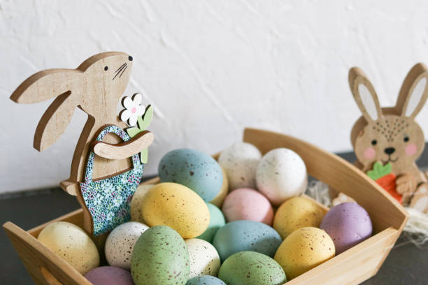 istock Wooden easter bunny with colorful eggs in a basket on grey table 2104649894